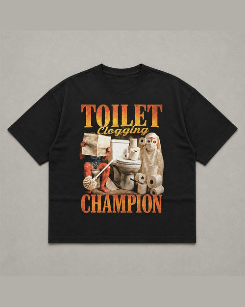 Black heavyweight tee reading TOILET CLOGGING CHAMPION in orange flame lettering around a bootleg collage of a toilet, rolls of paper and a plunger