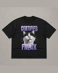 Black heavyweight tee reading CERTIFIED FREAK in purple chrome lettering above and below a close-up of a tuxedo cat
