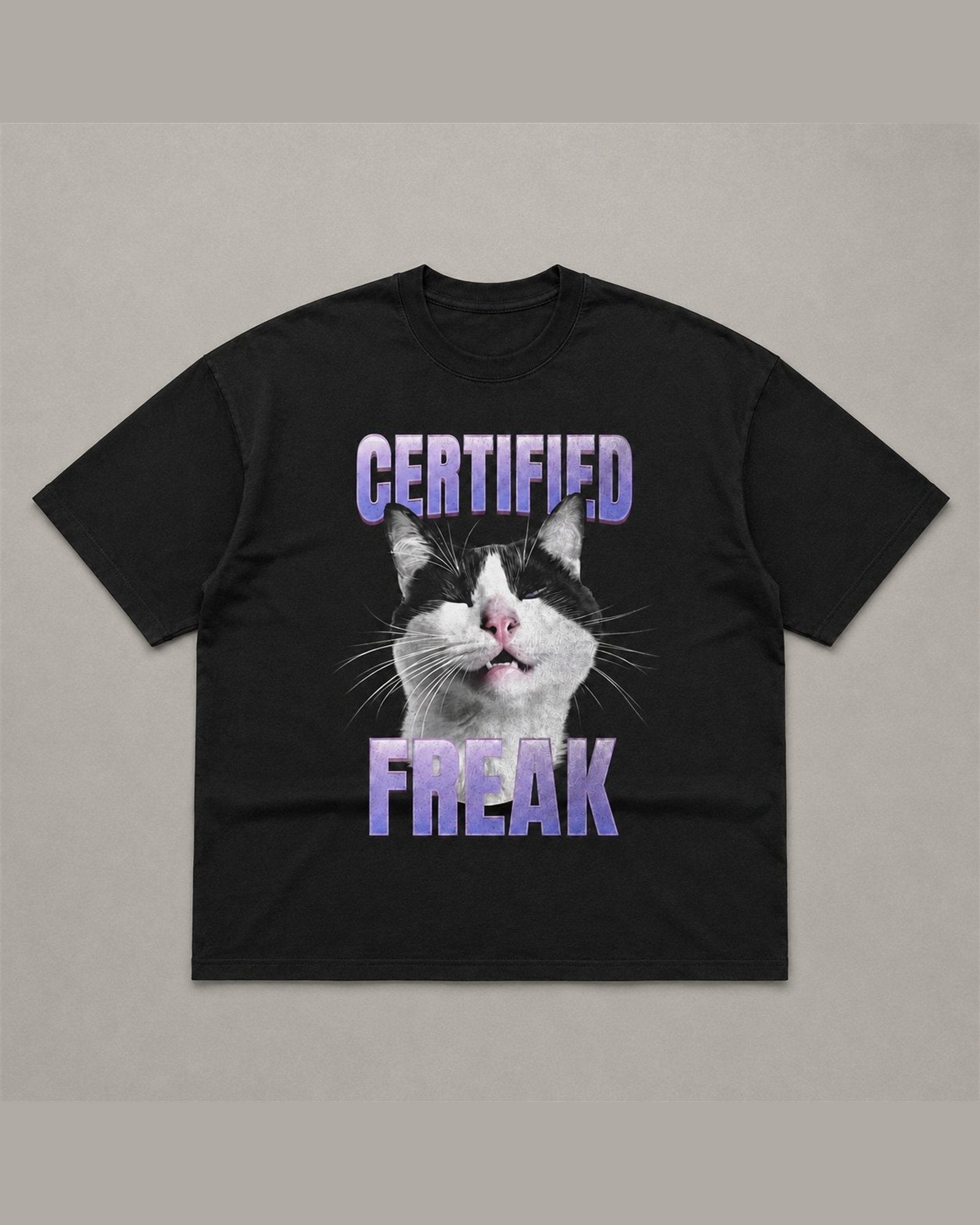 Black heavyweight tee reading CERTIFIED FREAK in purple chrome lettering above and below a close-up of a tuxedo cat